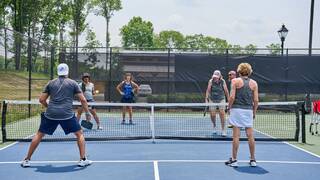 Two teams playing pickleball on an outdoor court.