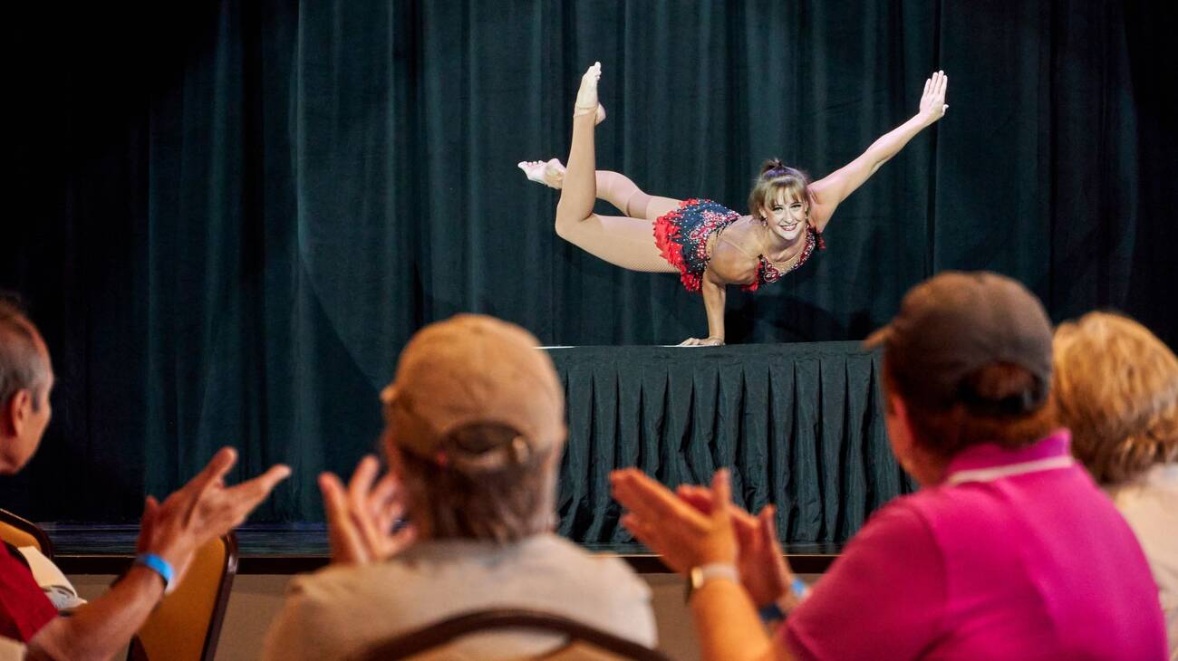 Amblebrook residents clapping as they watch a gymnast's performance on the community hall stage.